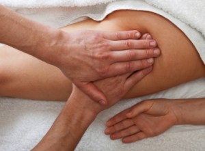 Massager's hands working with a woman's leg. Practice of reflexotherapy.